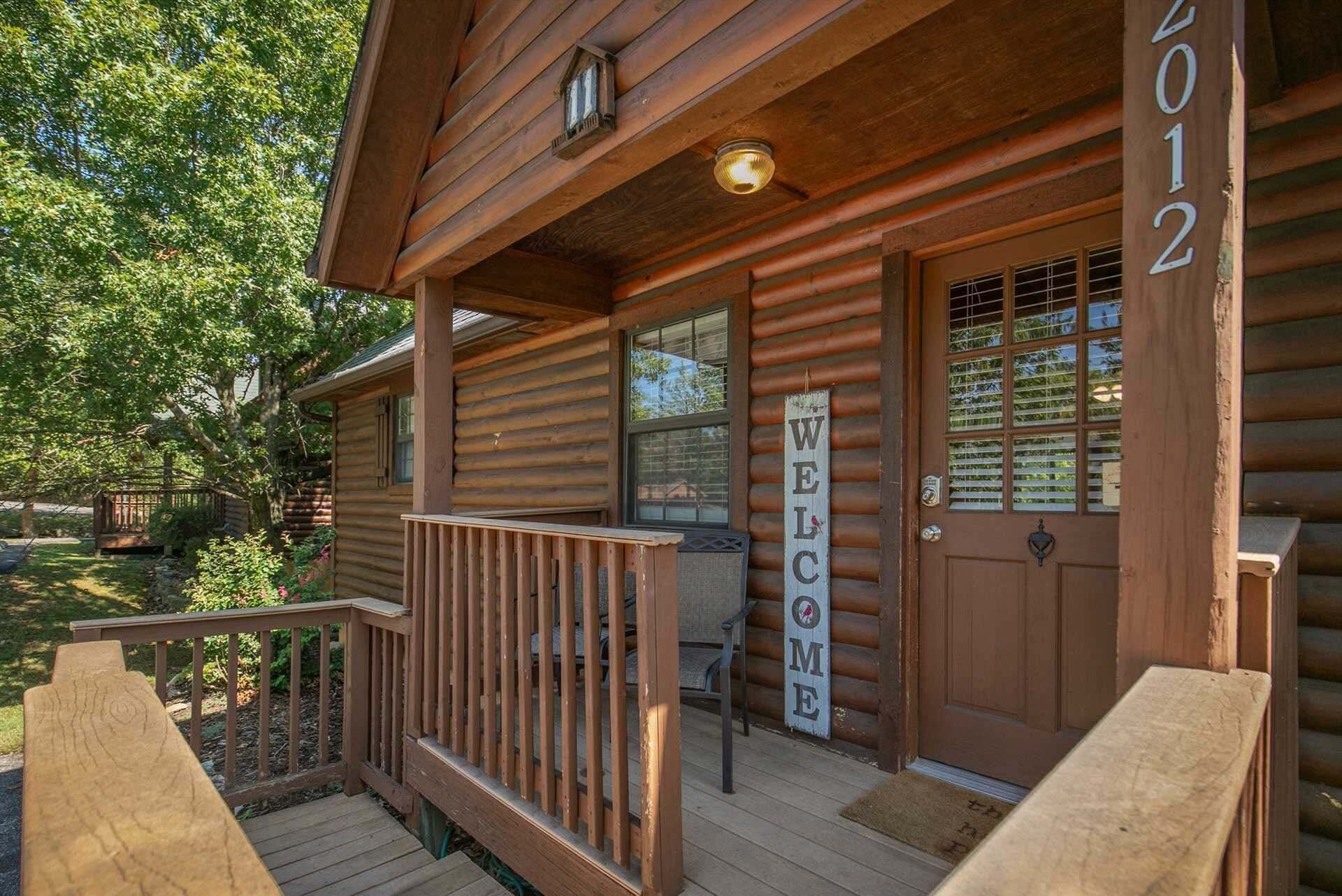 Eine Holzhütte mit Veranda, einem Willkommensschild und einer Tür mit der Aufschrift '2012'.