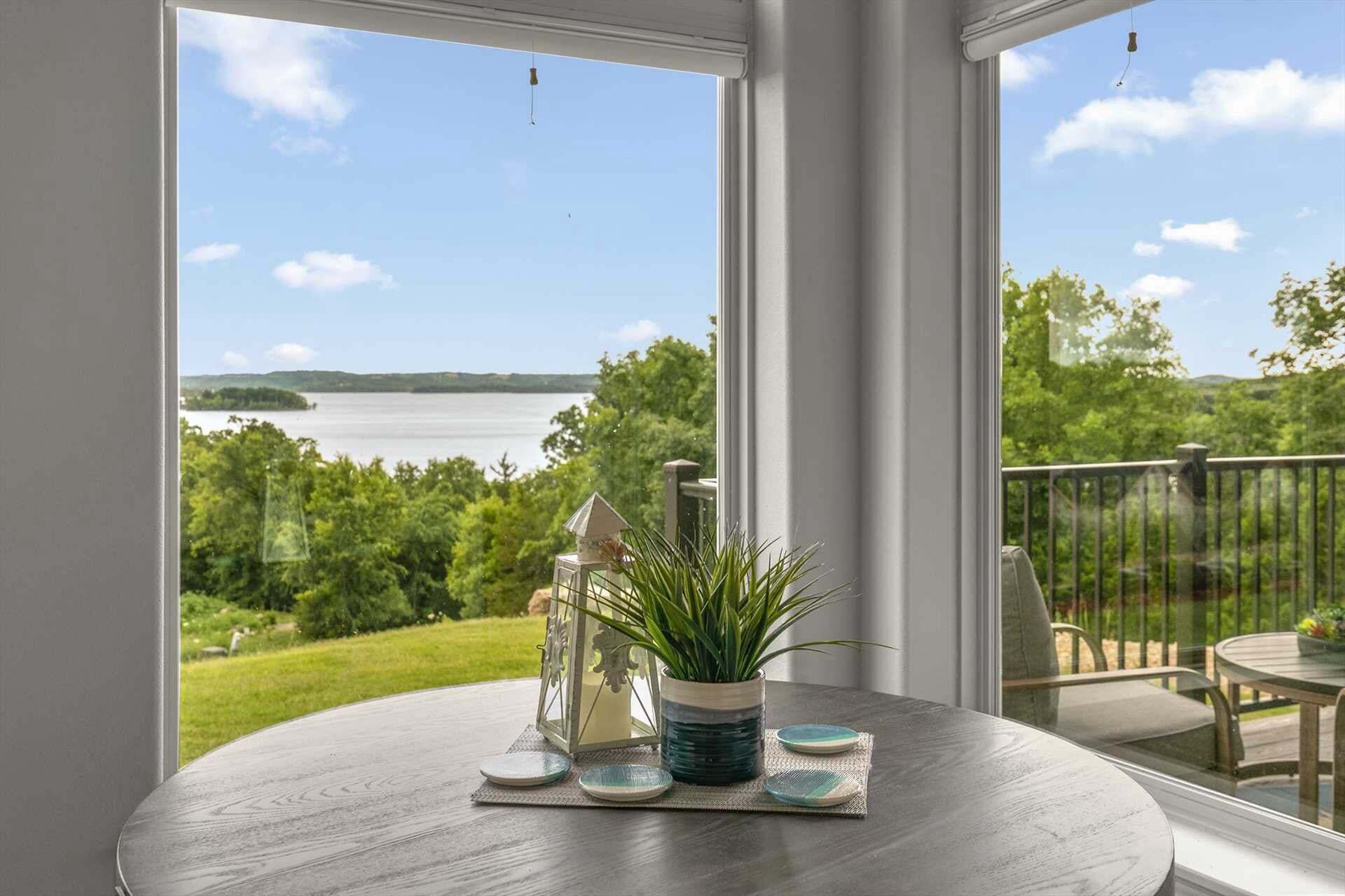 A round table with a view of a lake and greenery through large windows.