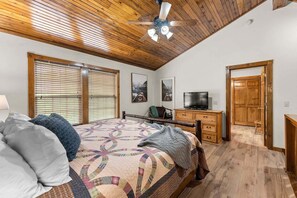 A bedroom with a wooden ceiling, a bed with a quilt, a desk with a TV, and a wardrobe. - Stonebridge Lodge, Water Views, Gated Community, Free Daily Attraction Tickets (Branson West)
