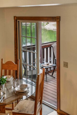 A dining area with a table set for two, a wooden chair, and a view through a glass door to an outdoor deck. - Stonebridge Lodge, Water Views, Gated Community, Free Daily Attraction Tickets (Branson West)