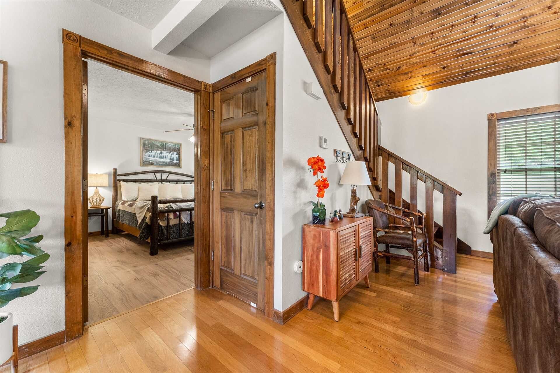 A wooden staircase leading to a bedroom with a bed and a nightstand.