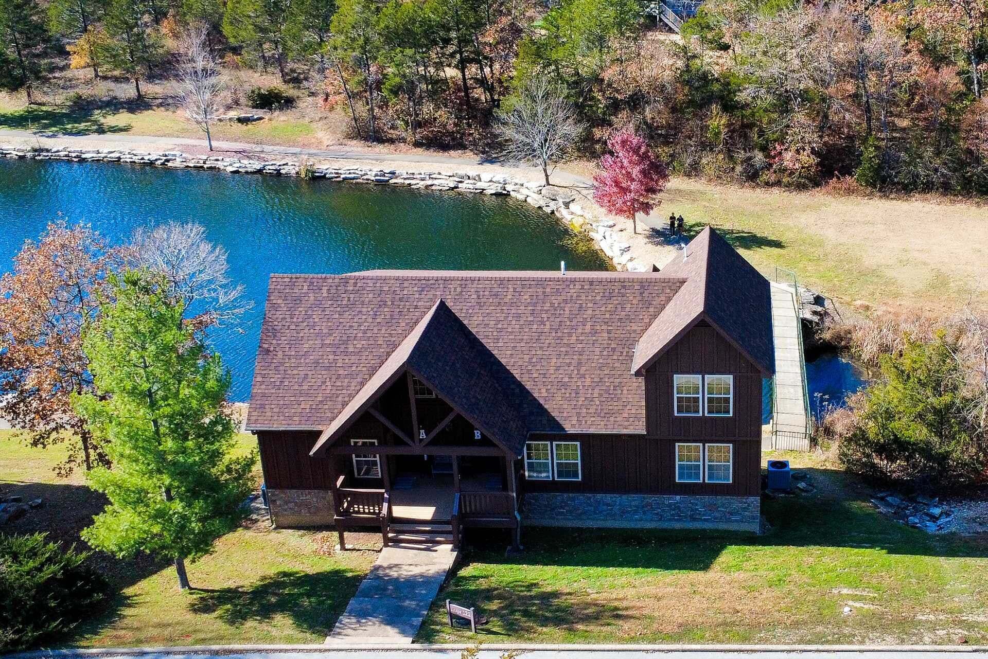 A two-story cabin with a stone foundation, a steeply pitched roof, and a front porch.