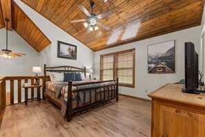 A bedroom with a wooden ceiling, a bed with a quilt, two bedside tables, a ceiling fan, and a television on a wooden stand. - Stonebridge Lodge, Water Views, Gated Community, Free Daily Attraction Tickets (Branson West)