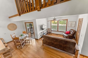 A spacious living area with a wooden floor, a brown sofa, and a dining table with chairs. - Stonebridge Lodge, Water Views, Gated Community, Free Daily Attraction Tickets (Branson West)