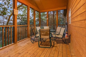 A wooden deck with a table and chairs, surrounded by glass windows. - Private lodge near Silver Dollar City, Beautiful Pool,. Fishing Lake, Ramp Entry, Vaulted Ceilings (Branson West)