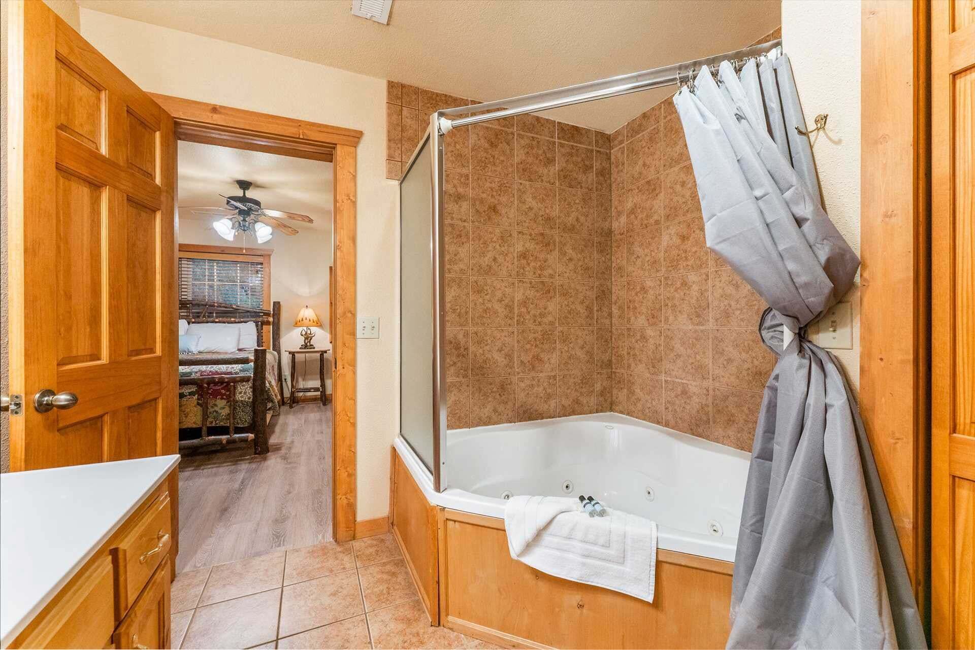 A bathroom with a bathtub, shower curtain, and wooden flooring.