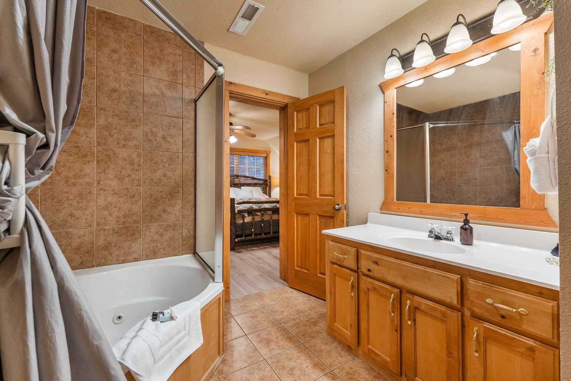 Une salle de bain avec une baignoire, un grand miroir, des meubles en bois et un espace douche.