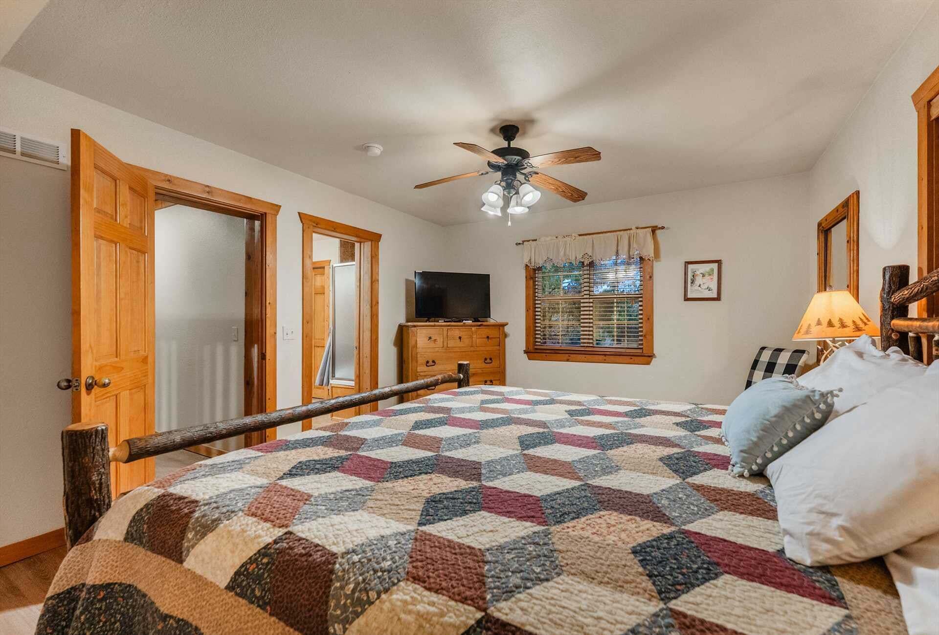 A bedroom with a bed, a ceiling fan, a television, and a window with blinds.