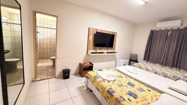 A hotel room with a bed, a TV mounted on the wall, a small desk, and a window with curtains. - Pousada Oásis do Cariri (Juazeiro do Norte)