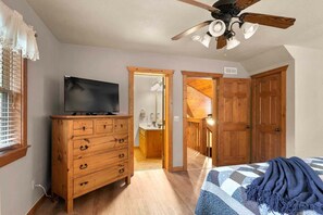 A bedroom with a bed, a wooden dresser, a television, and a ceiling fan. - Near SDC, Private Lake and Fishing, Free Daily Attraction Tickets (Branson West)