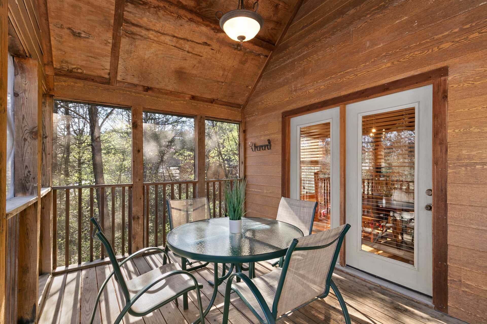 A wooden deck with a glass table and chairs, a potted plant, and a door with blinds.