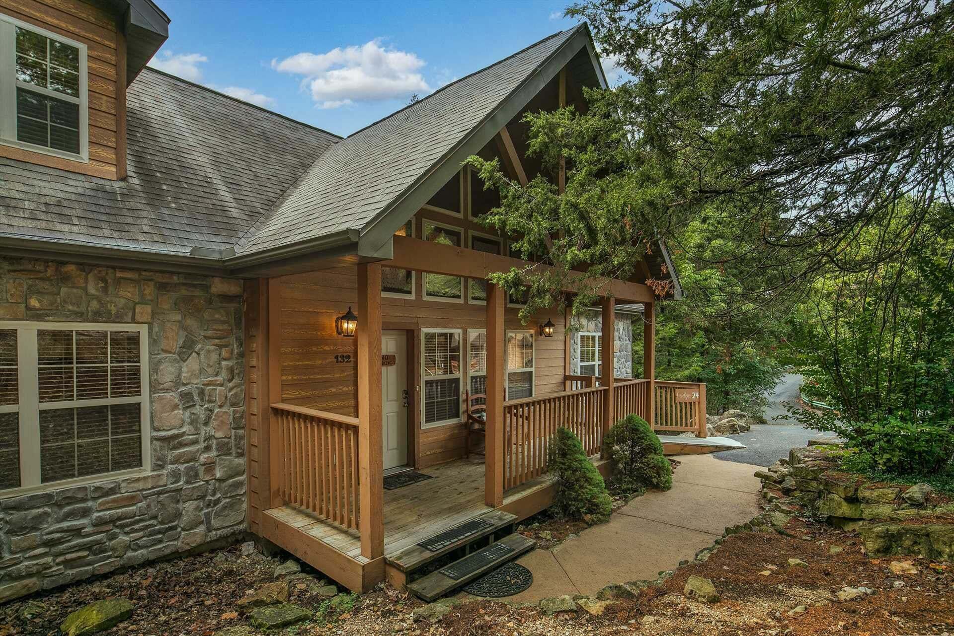 A two-story stone house with a wooden porch, stone walls, and a stone staircase leading to the entrance.