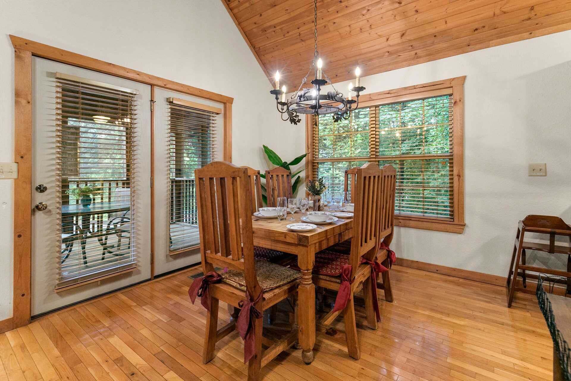 A dining area with a wooden table set for four, surrounded by chairs.