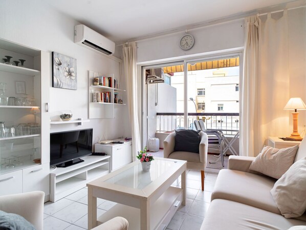 Ein modernes Wohnzimmer mit Flachbildfernseher, Couchtisch, Sofa und einem Balkon mit Stadtblick.