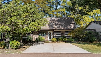 A two-story house with a stone facade, a front porch, and a mailbox.