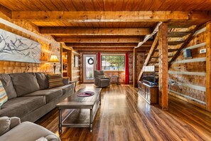 A cozy interior with a wooden ceiling, a sofa, a coffee table, and a TV on a wooden cabinet.