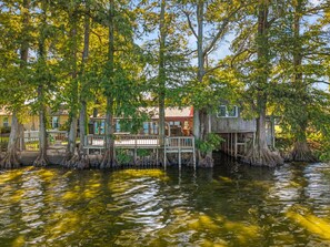 A house built on stilts over water, surrounded by trees.