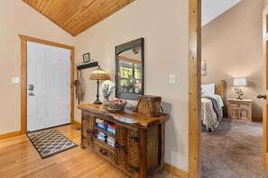 A wooden door, a console table with a lamp, a mirror, and a bed with a nightstand. - "Mighty Oaks" Stonebridge Lodge -  Double King Masters-Free Daily Attraction Tickets (Branson West)