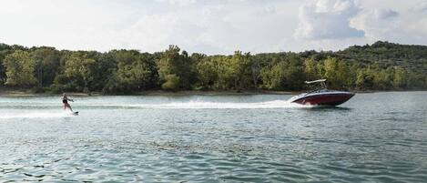 Un cos d'aigua amb un wakeboarder i un vaixell ràpid.