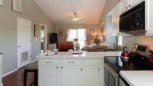 Una cocina con armarios blancos, estufa y microondas.