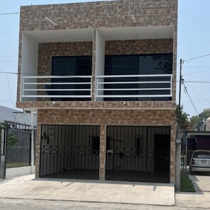 A two-story building with a balcony on the upper floor, a gated entrance, and a clear sky. - Hotel Alex (Cunduacán)