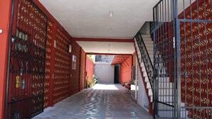 A corridor with a tiled floor, red walls, and a staircase with metal railings.