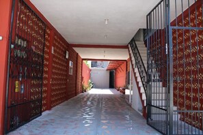 A corridor with a tiled floor, red walls, and a staircase with metal railings.