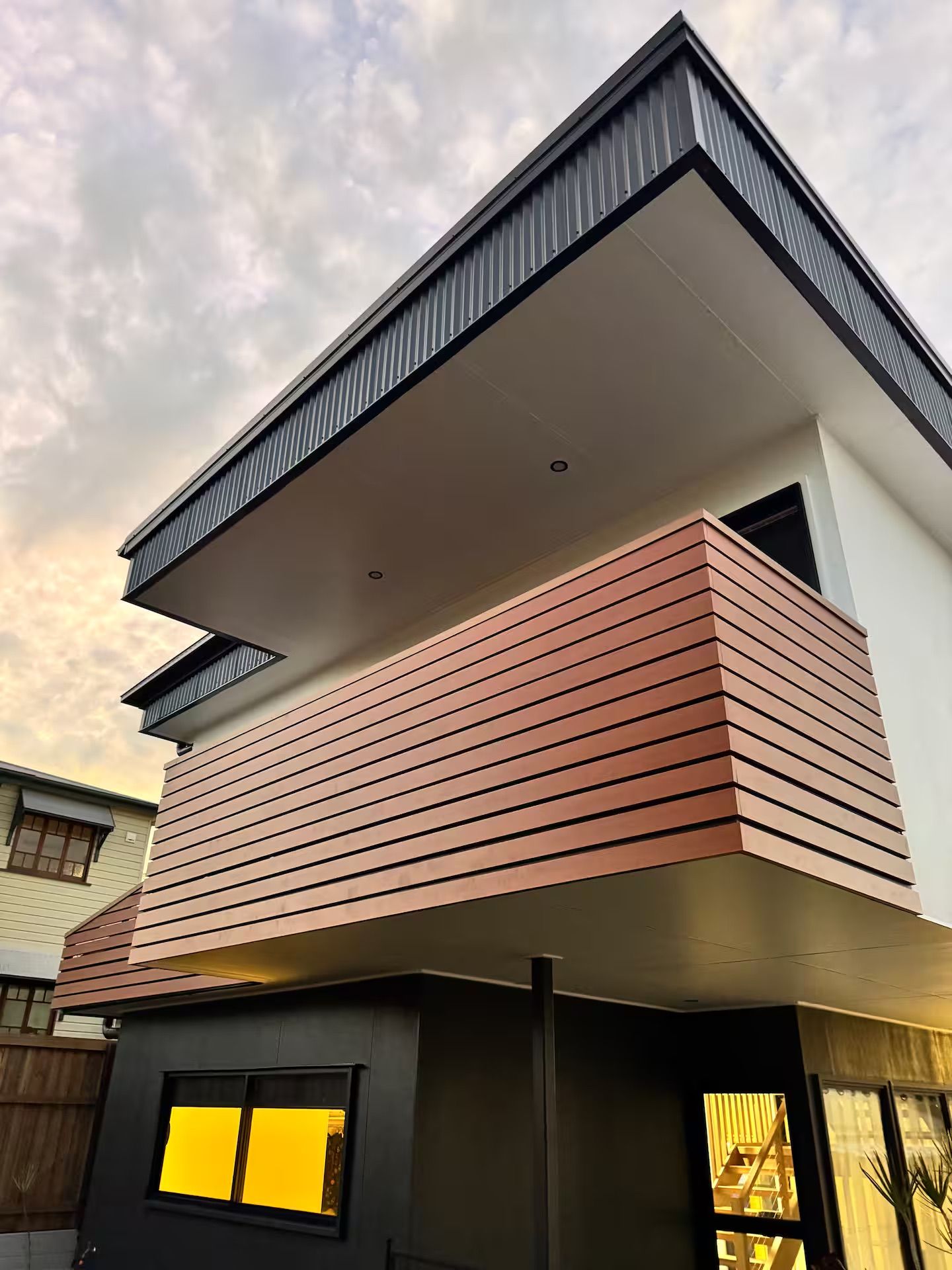 A modern two-story building with a flat roof and a balcony.