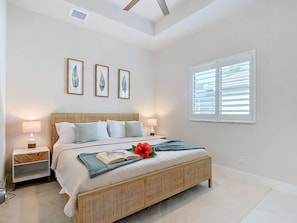 A bedroom with a bed, bedside tables, a window with blinds, and wall-mounted artwork. - 5 Bedroom, Saltwater Heated Pool & Spa, Dock: The Coastal Cabana (Cape Coral)