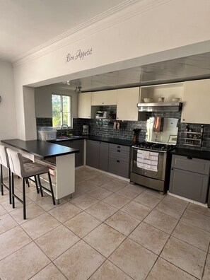 A modern kitchen with a central island, dark backsplash, and stainless steel appliances. - 3BR Villa with Private Pool & Beach Access - Sleeps 6 (Punta Cana)