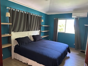 Een slaapkamer met een bed, gordijnen, een raam en een staande lamp.