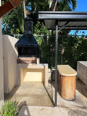 An outdoor barbecue area with a brick oven, a wooden table, and a metal roof structure. - 3BR Villa with Private Pool & Beach Access - Sleeps 6 (Punta Cana)