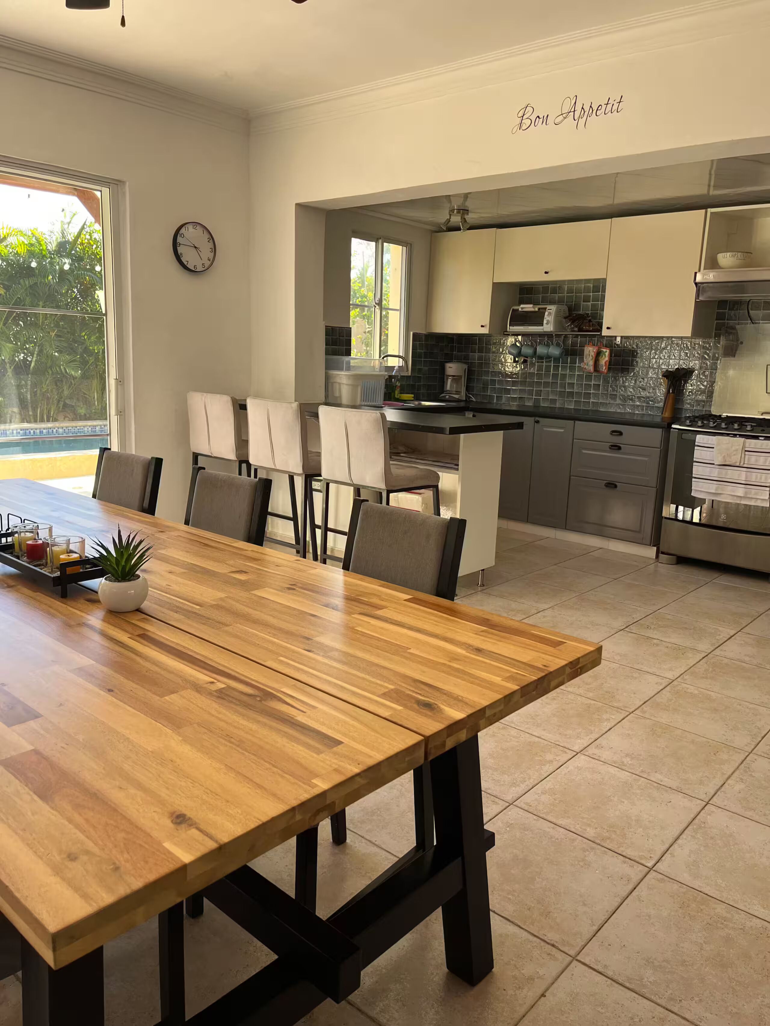 Una cucina moderna con un tavolo da pranzo in legno, sedie e un orologio appeso al muro.