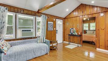 A cozy room with a wooden interior, a sofa, a small table, and a bed.