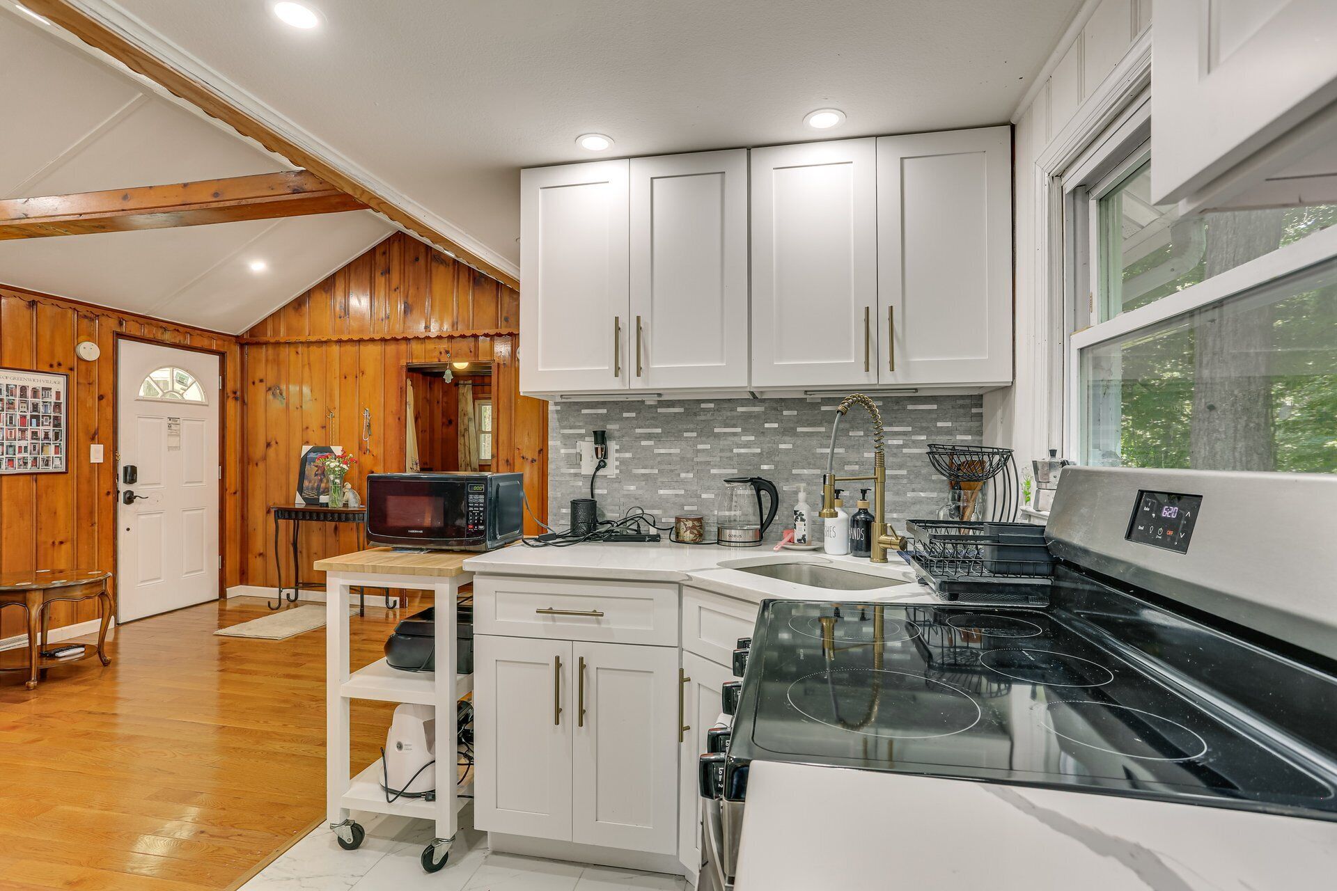 A modern kitchen with white cabinets, a black stove, and a window.