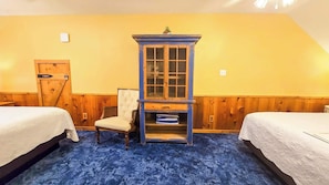 A room with two beds, a blue cabinet with glass doors, a chair, and a wooden door. - Utopia Gruene Cottages (New Braunfels)