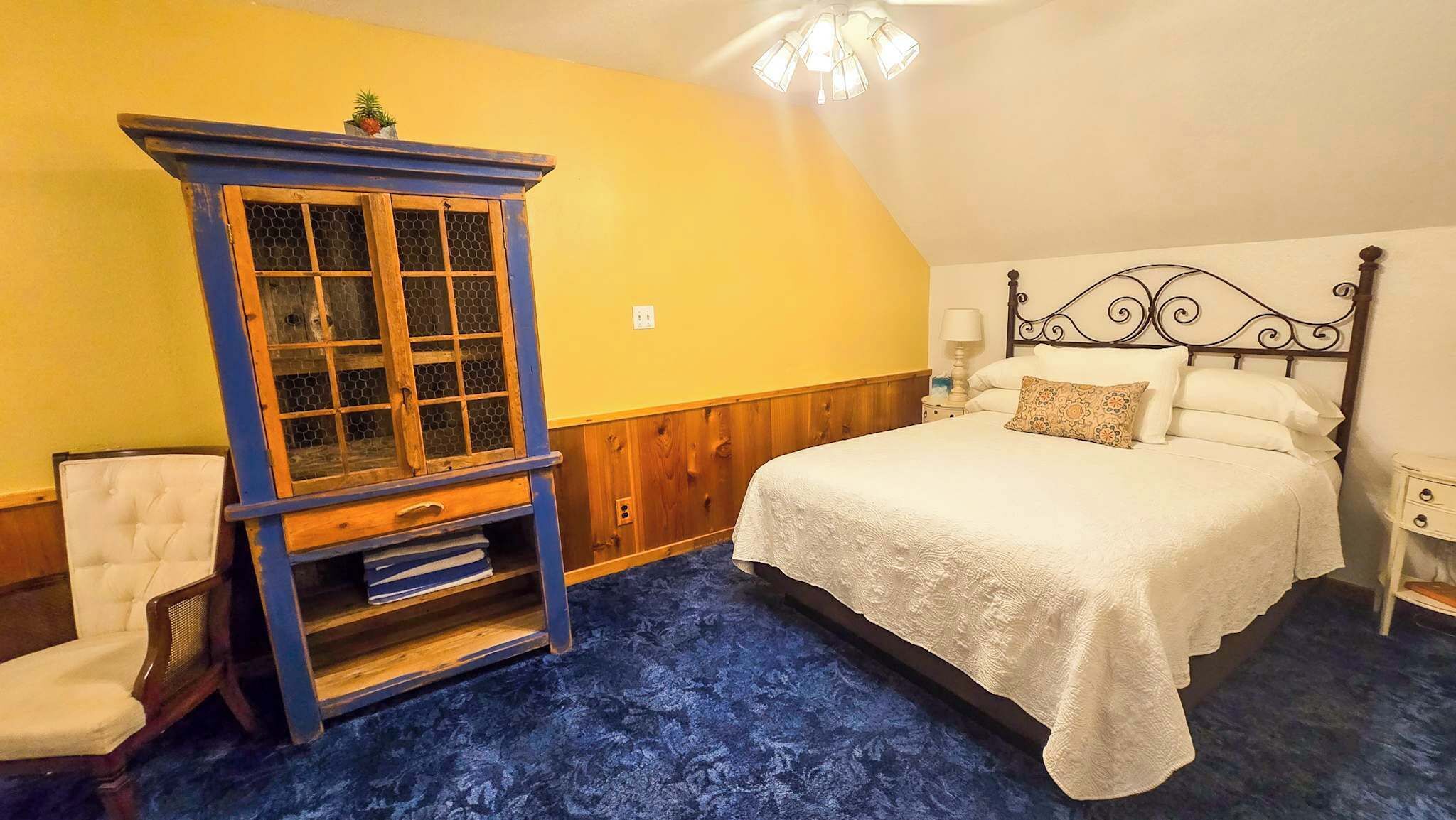 Un dormitorio con una cama, una mesita de noche, un aparador y una silla.