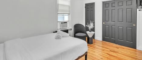 Une chambre à coucher avec un lit, une chaise, un radiateur et deux portes.