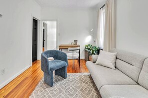 Ein modernes Wohnzimmer mit einer Couch, einem blauen Sessel, einem Holztisch und einer Topfpflanze.