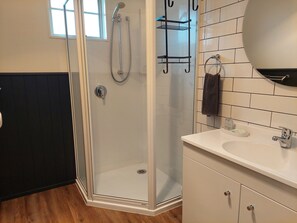 A modern bathroom with a glass-enclosed shower, a white sink with a mirror, and a towel rack. - Colonial On Tay Motel (Invercargill)