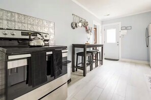 A kitchen with a stove, oven, and hanging pots. There is a small bar area with stools.