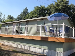 A single-story mobile home with a covered porch and a blue umbrella.