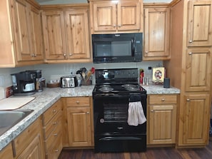 A kitchen with wooden cabinets, a microwave, a stove, and a toaster.