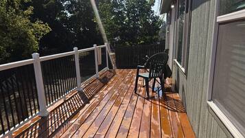 Eine Holzterrasse mit Geländer, einem Stuhl und einem Tisch.