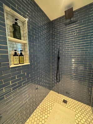 A bathroom with blue-tiled walls, a white shelf with toiletries, and a hexagonal patterned floor. - Peaceful private room and kitchenette in Boulder (Boulder)