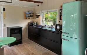 A compact kitchen with a vintage-style refrigerator, a built-in oven, and a window providing a view of greenery outside. - 4 bedroom stunning home in Tisvildeleje (Tisvildeleje)