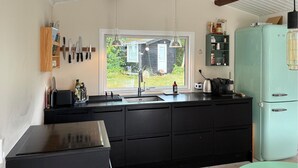 A kitchen with a black countertop, a sink, a window with a view of a house, and a teal refrigerator. - 4 bedroom stunning home in Tisvildeleje (Tisvildeleje)