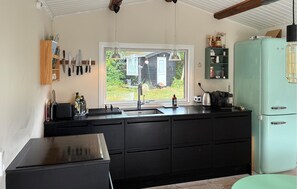 A kitchen with a black countertop, a sink, a window with a view of a house, and a teal refrigerator. - 4 bedroom stunning home in Tisvildeleje (Tisvildeleje)