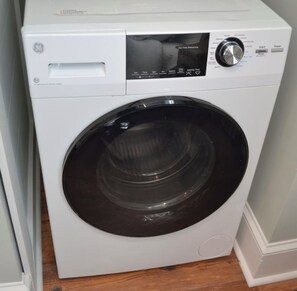 A front view of a white front-loading washing machine with a control panel on top.