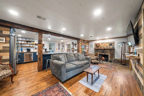 A spacious living area with a gray sofa, wooden flooring, and a fireplace.
